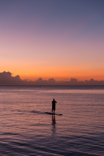 man paddleboarding during sunset