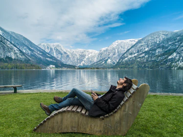 Person relaxing by a mountain lake 