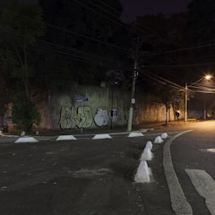 A gritty urban street scene at night with graffiti walls and dim streetlights.
