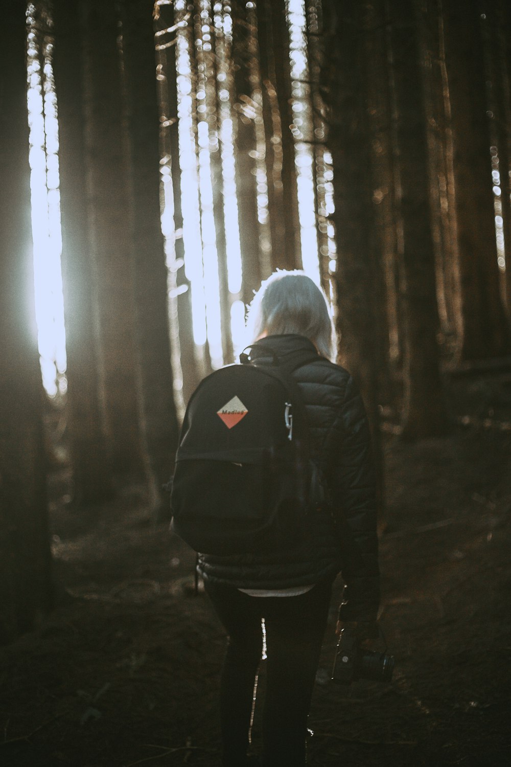 person carrying backpack walking towards trees