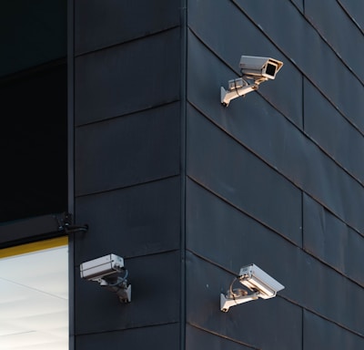 three white CCTV camera on building wall