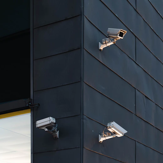 Modern security cameras mounted on a commercial building exterior.