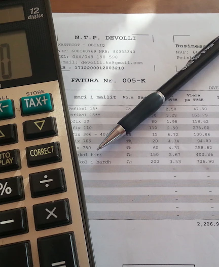 Close-up of hands signing a vehicle financing contract with legal documents and a calculator nearby.