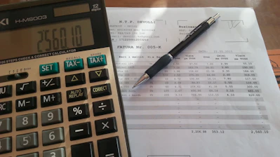 Close-up of financial documents and a calculator on a wooden desk.