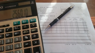 Close-up of hands calculating numbers with a calculator and financial papers.