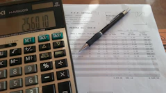 Close-up of hands reviewing financial documents with a laptop and pen.