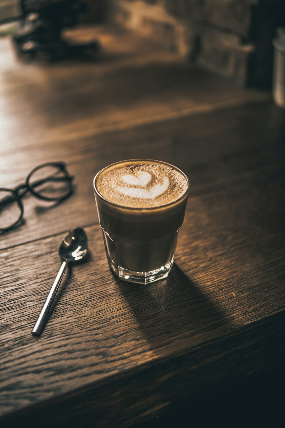 cappuccino with heart latte art on brown wooden table surface