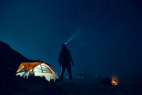 man standing beside camping tent wearing headlamp during nighttime in Korlai Fort India