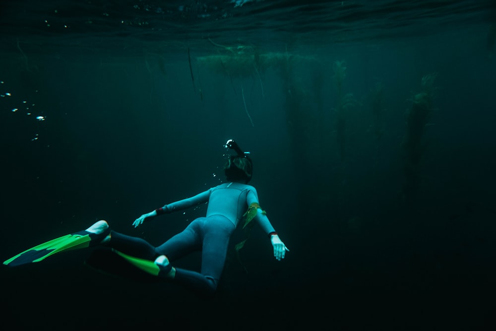 persona bajo el agua con un par de aletas durante el día
