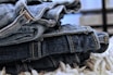 Close-up of soft, textured fabrics in various shades of denim jeans stacked on wooden shelves.