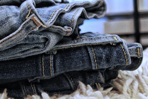Close-up of folded denim jeans stacked neatly on a rustic wooden shelf