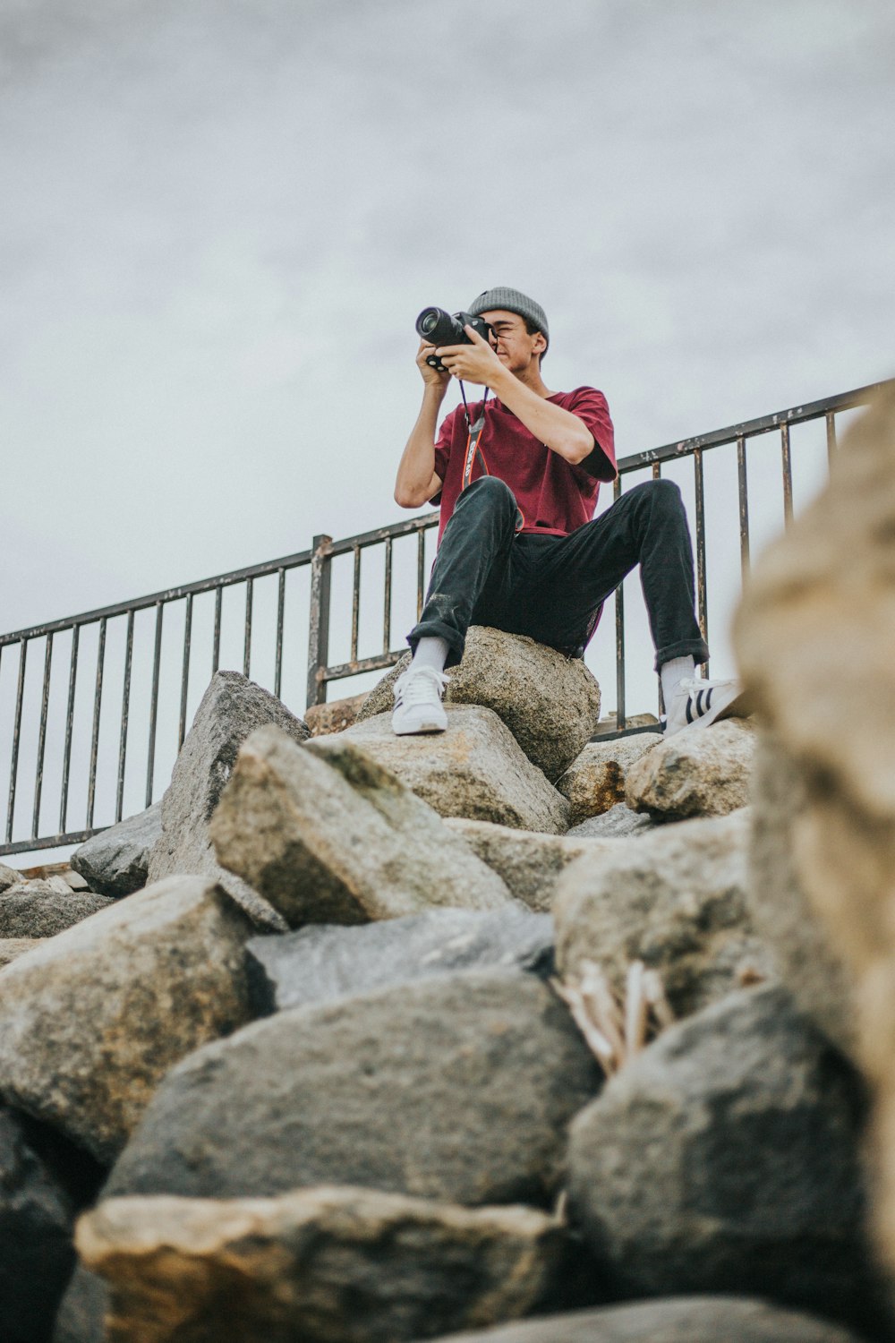 person sitting on rock holding black DSLR camera