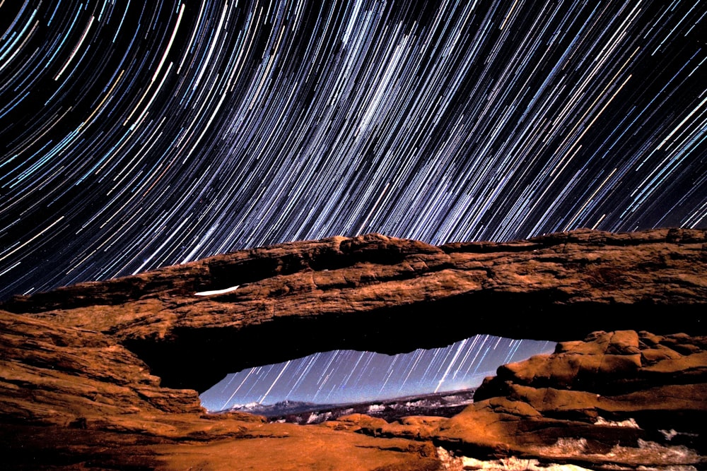 timelapse photo of stars and brown rock arch