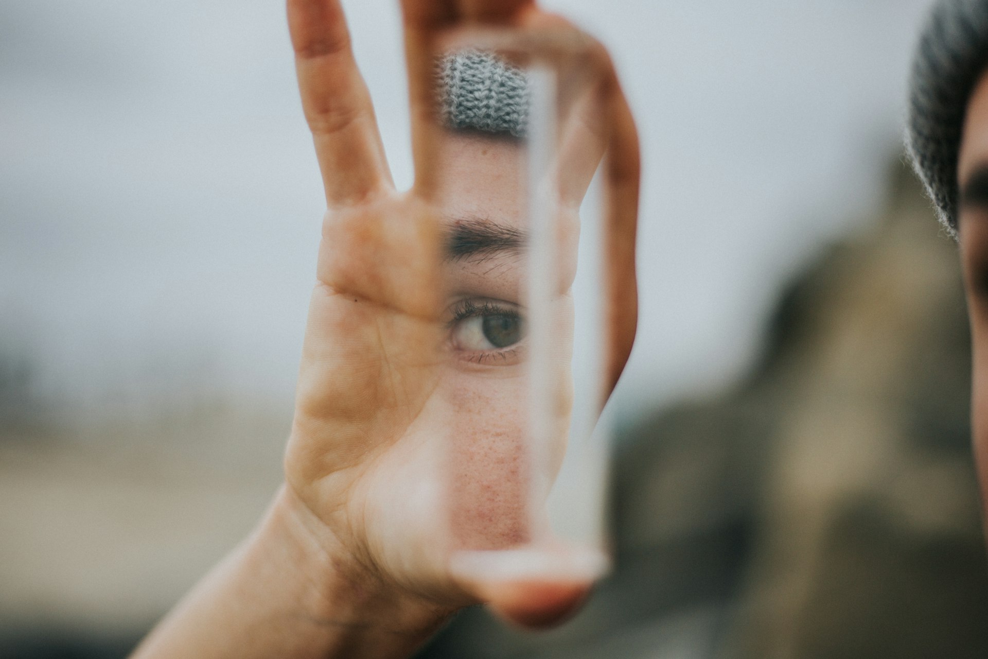 Shallow-focus portrait of a person holding a small mirror, self-reflection register.