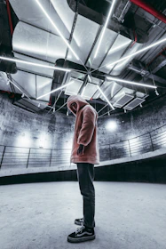 Model wearing a sleek black hoodie with futuristic patterns in an industrial setting.
