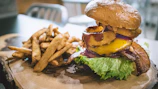 Burger Fast served with a side of golden fries on a rustic wooden board.
