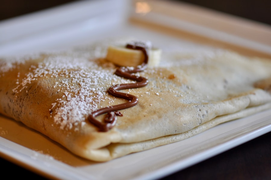 A folded buckwheat crepe dusted with sugar on a white plate