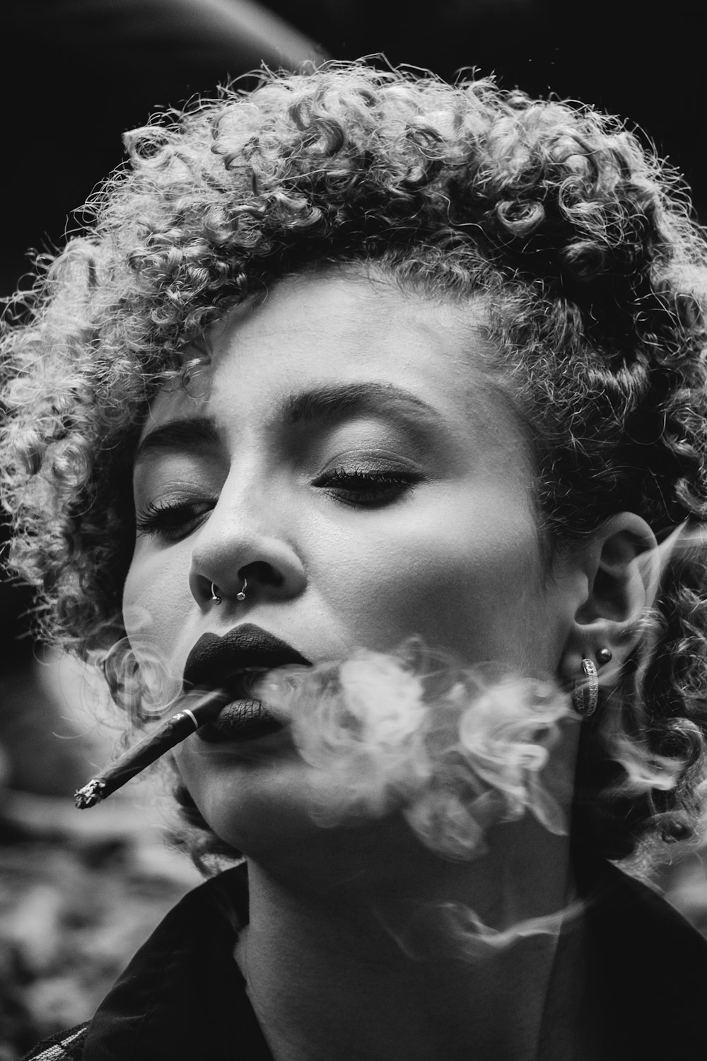 Foto en escala de grises de una mujer fumando