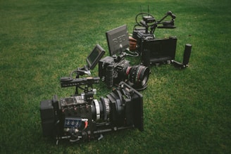 three black video cameras on green grass field