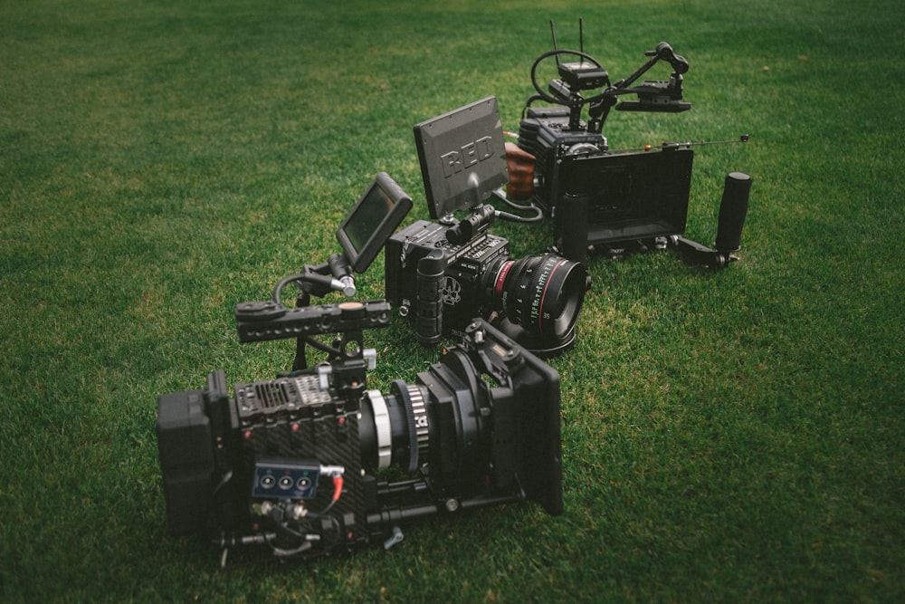 three black video cameras on green grass field