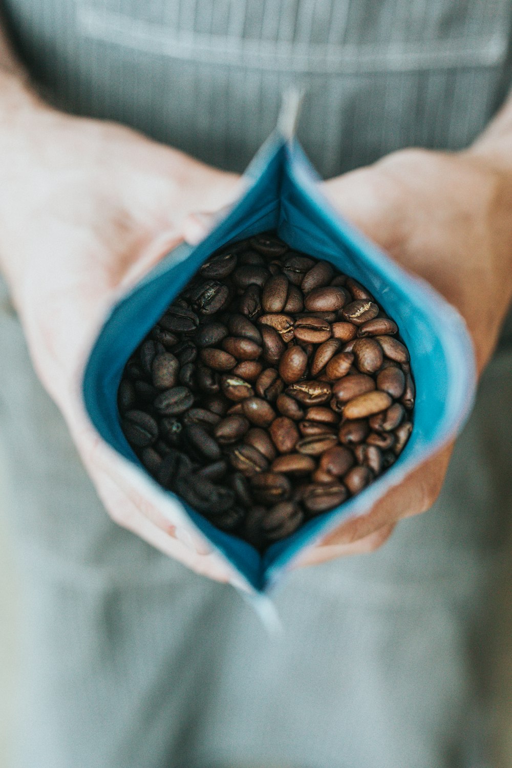 persona che tiene i chicchi di caffè in confezione