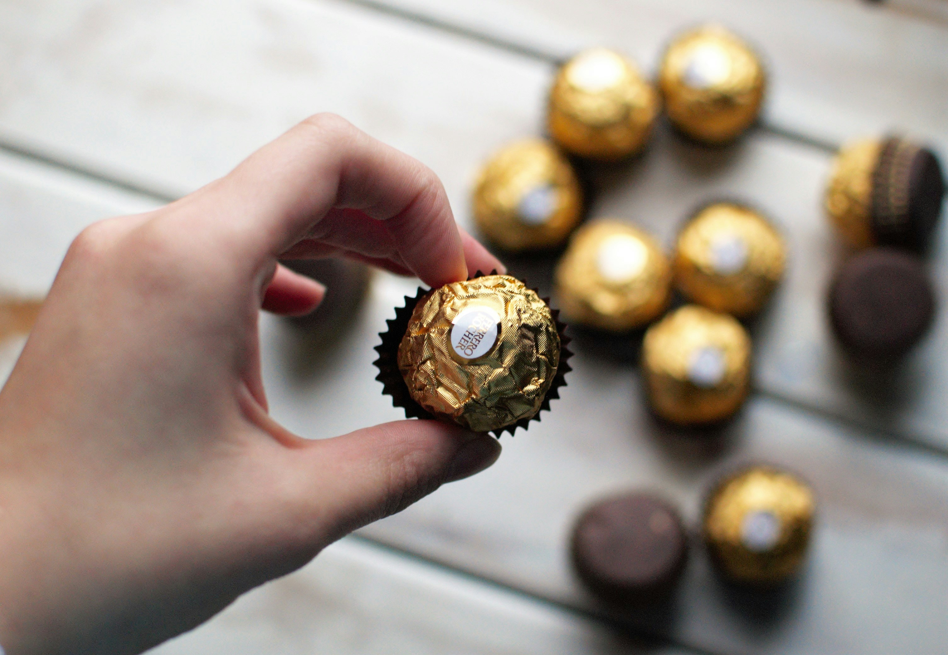 Elegant gold Ferrero Rocher chocolate box open showing hazelnut truffles, warm studio lighting, rich background