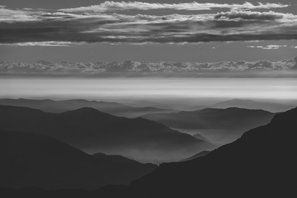 grayscale photography of clouds through mountain range