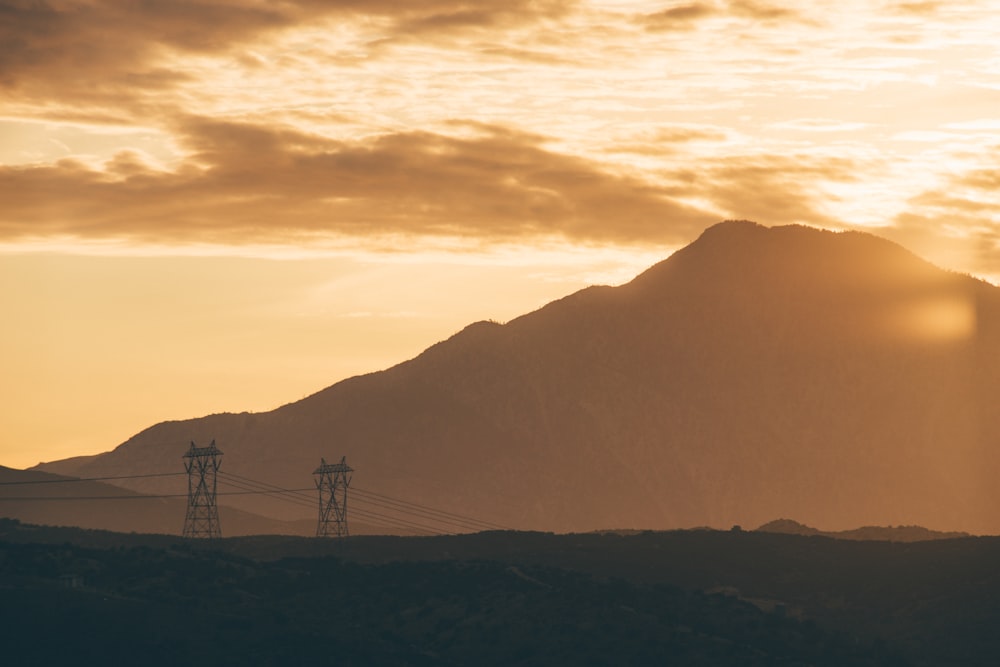 sun shining over mountain and two transmission towers