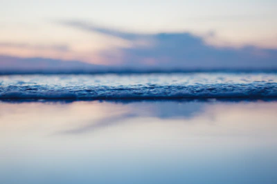 A minimalist seascape with calm waves and a pastel sky at dusk.