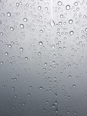 A clear glass of water with droplets on the outside, set against a soft blue background symbolizing freshness.