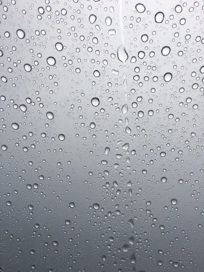 A clear glass of water with droplets on the outside, set against a soft blue background symbolizing freshness.