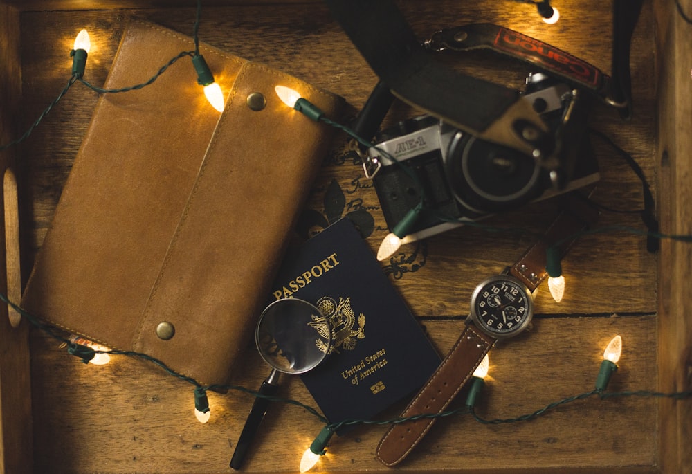 passport and SLR camera on table with string lights