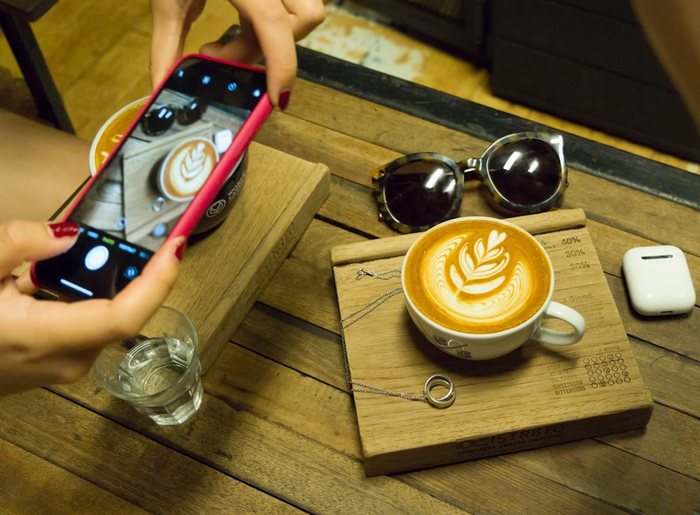 person taking photo of latte art