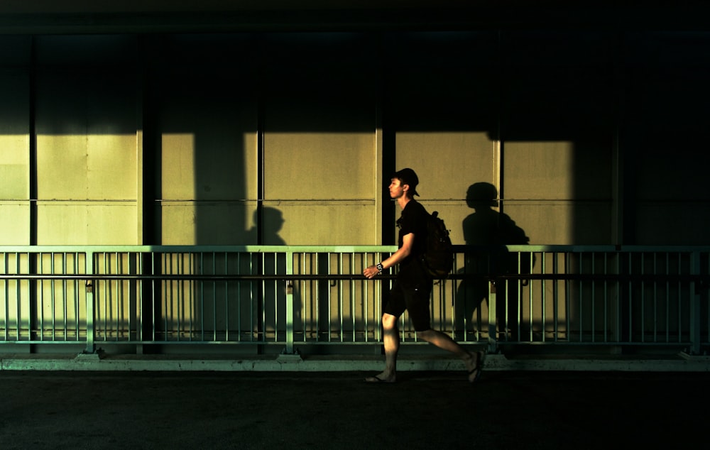 man walking beside gray metal fence