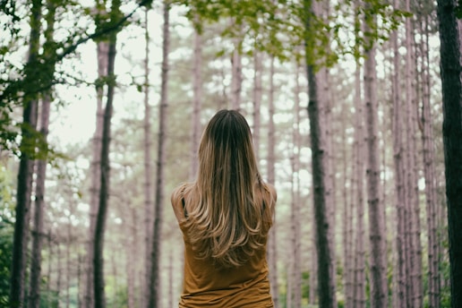 woman in brown shirt fronting trees