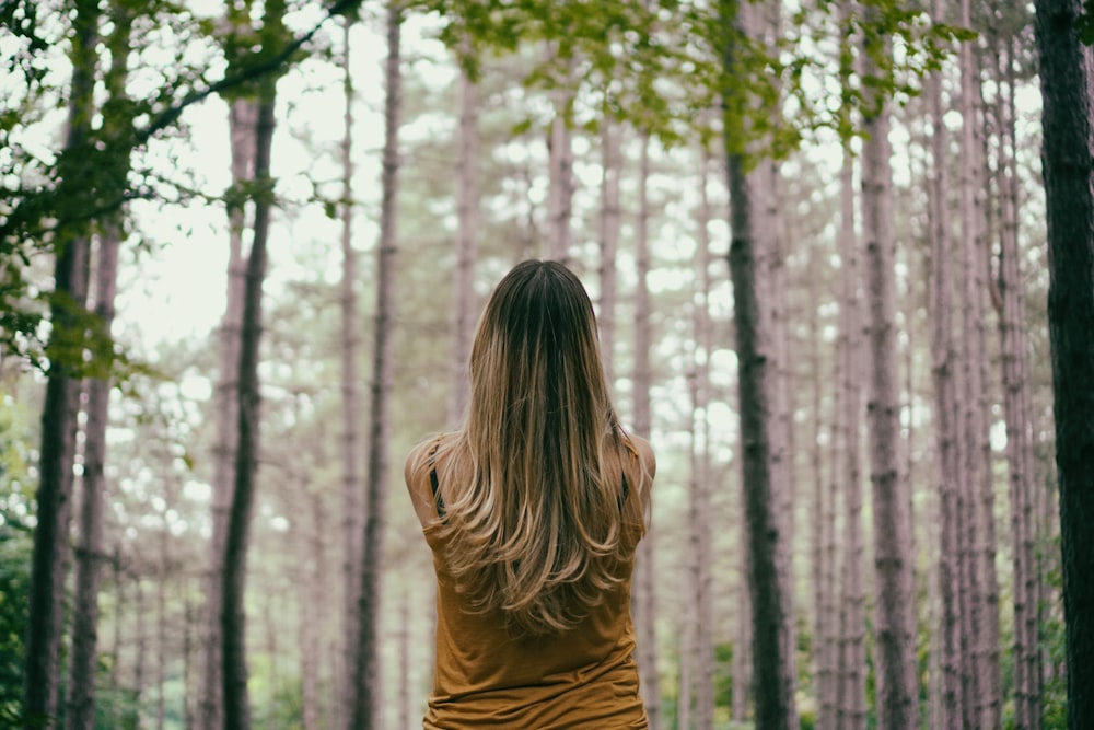 woman in brown shirt fronting trees