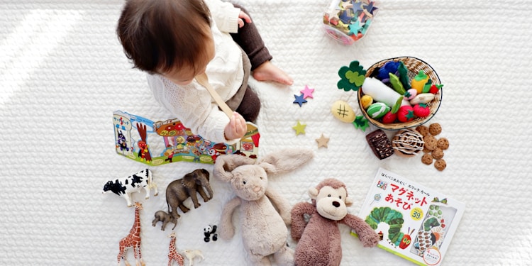boy sitting on white cloth surrounded by toys
