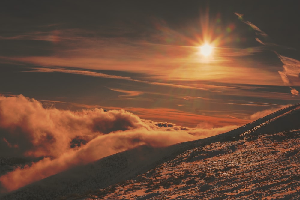 grayscale photo of sun's ray above the clouds