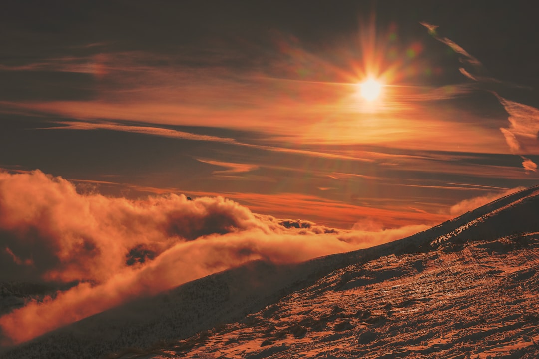 grayscale photo of sun's ray above the clouds