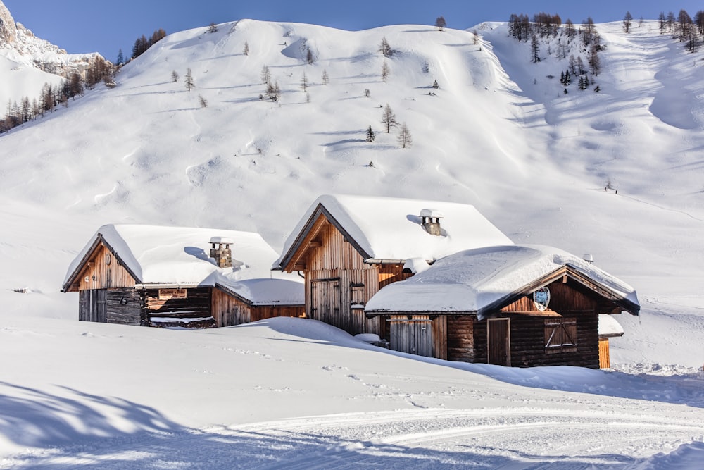 um grupo de edifícios de madeira sentados no topo de uma encosta coberta de neve