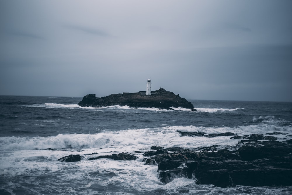 Faro blanco en formación rocosa rodeada por el océano