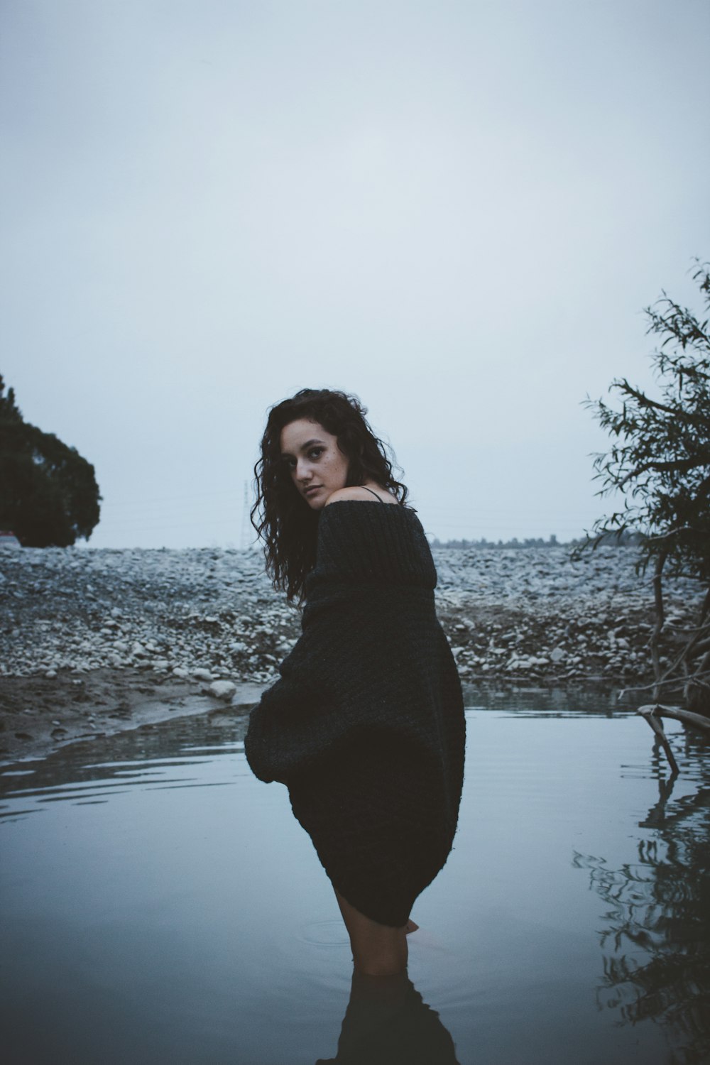 woman on body of water near tree