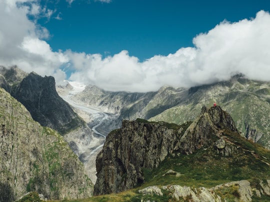 brown and green rock formation under blue and white clouds in Fiescher Glacier Switzerland