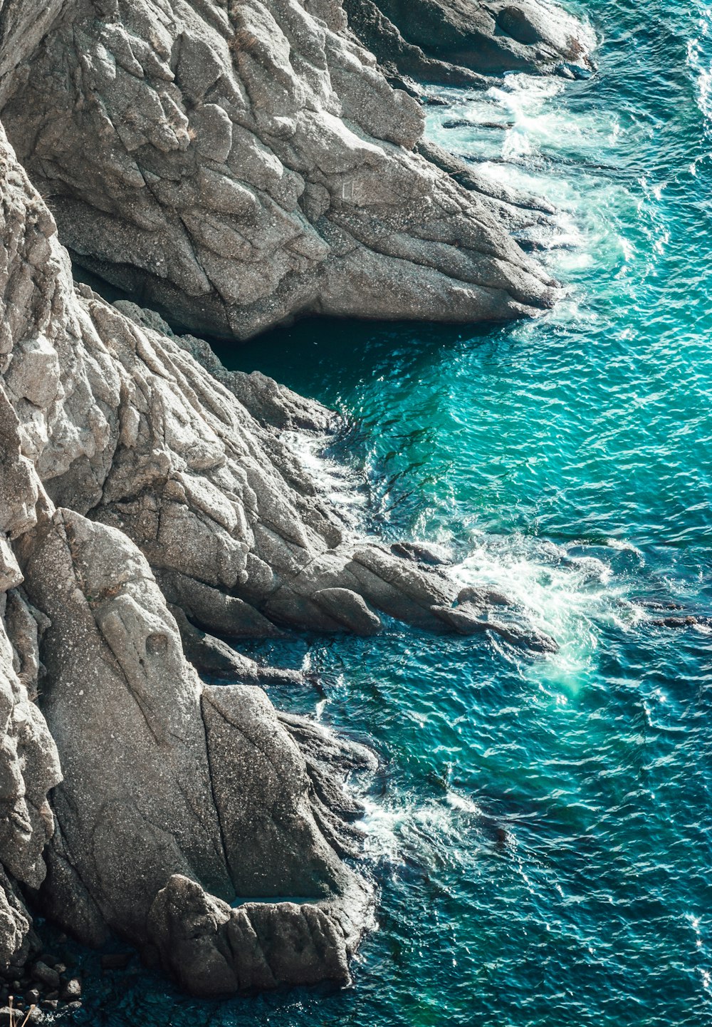 gray cliff near body of water at daytime