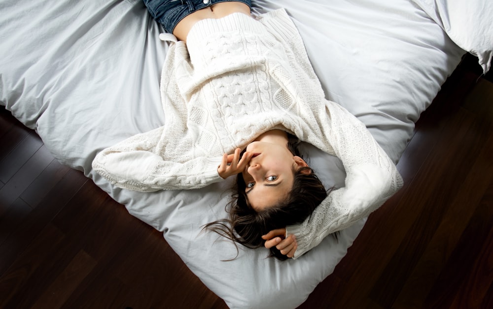 woman lying on bed with white bedspread