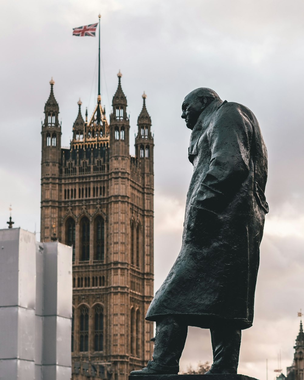 homme portant une statue de manteau montrant un bâtiment avec un drapeau