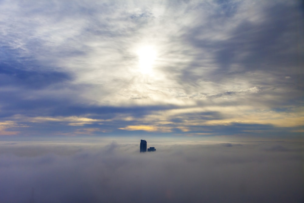 Photo d’un bâtiment noir entouré de nuages pendant la journée