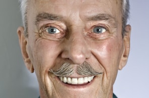 A close-up portrait of an elderly Allen with a warm, welcoming smile.