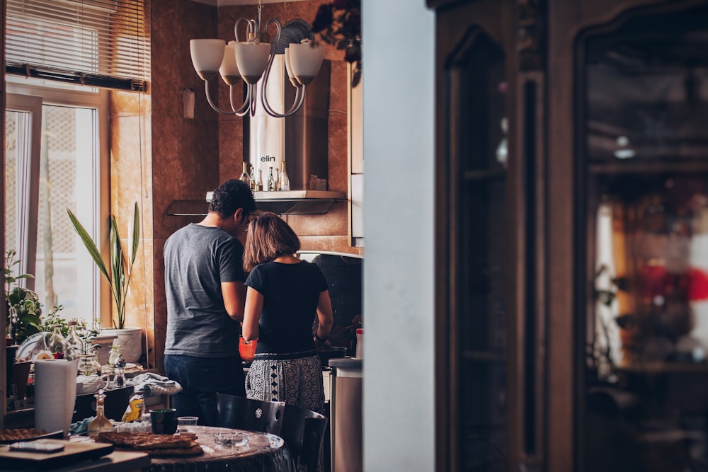 homme et femme debout devant la cuisinière à gaz
