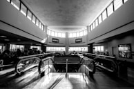 A modern escalator ascending inside a bustling airport terminal in Qatar with travelers and luggage.